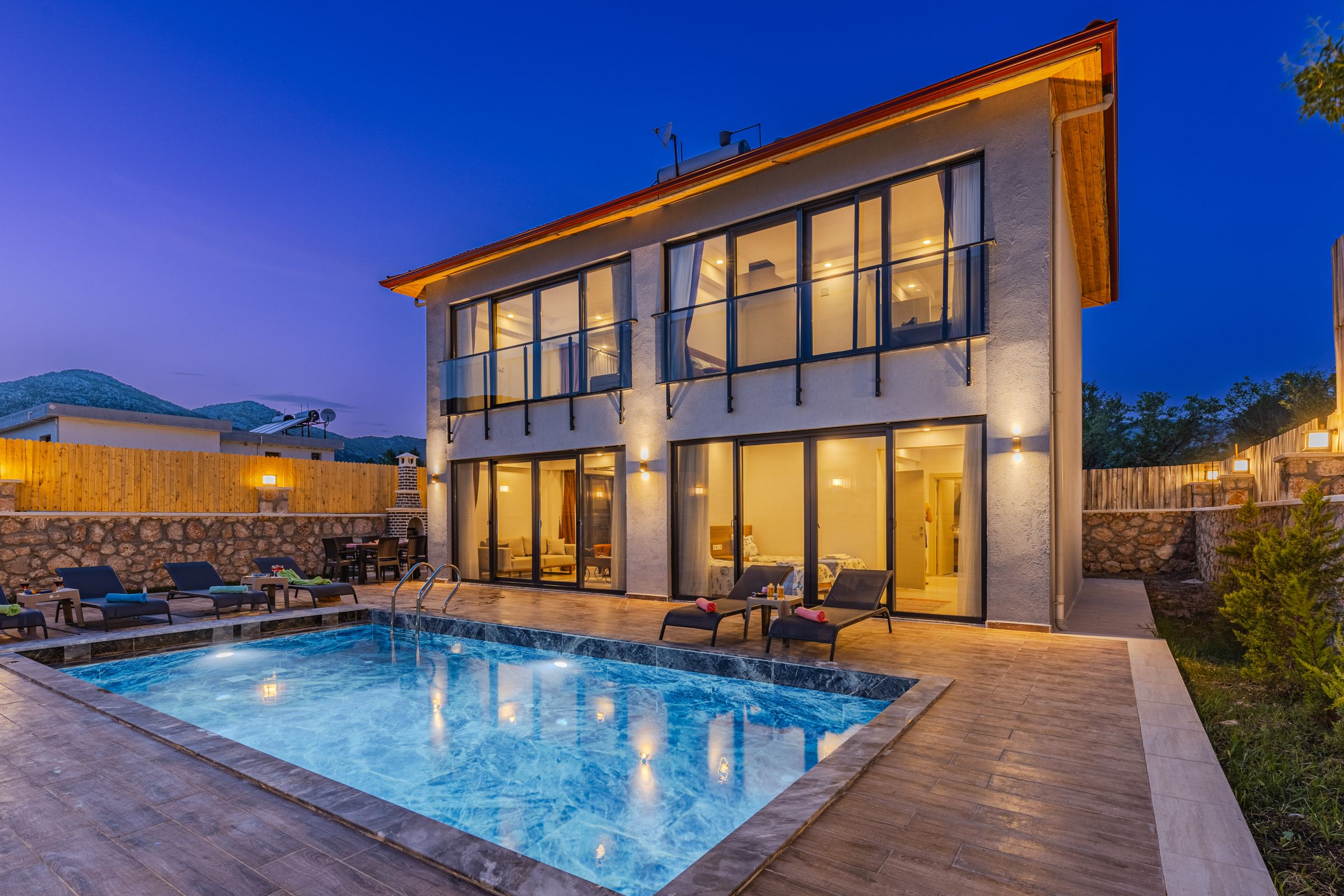 Architectural inspiration: a luxury home with warmly lit windows and a pool at dusk